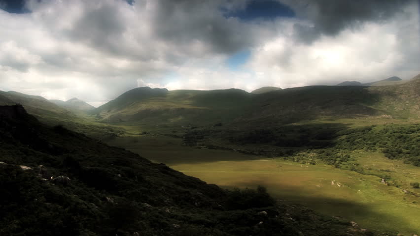 A valley on the west coast of Ireland is bathed in the shadows and streams of sunlight rushing overhead.