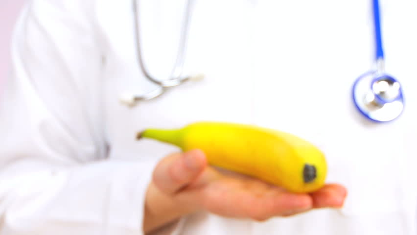 Doctor in white coat suggesting eating a banana as a healthy food option