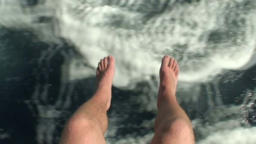 Mans legs hanging over the side of a boat