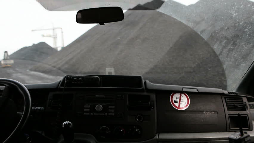 lose up of dashboard whilst driving though piles of coal, and seeing cranes an lorries