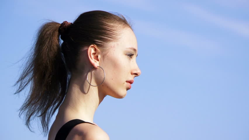 Girl on the background of nature. Beautiful girl fashion model sitting on a rock against the beautiful natural scenery. Motion zoom.