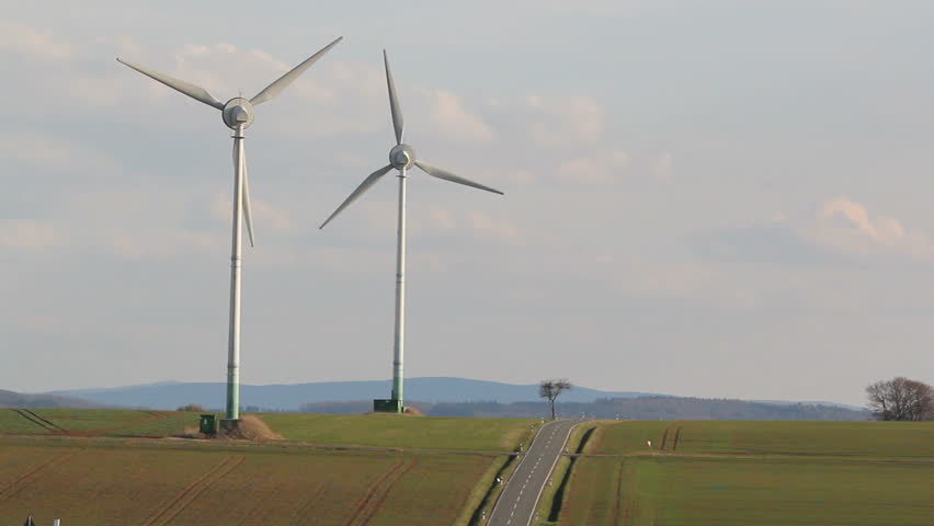 two wind turbines near a road in rural German landscape 