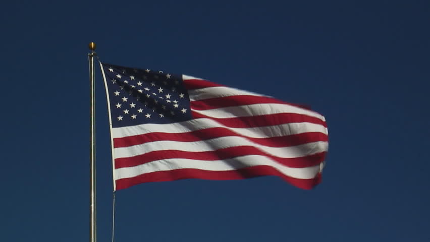 real United States of America flag flying on flagpole against clear blue sky - HD, no audio, zoom in