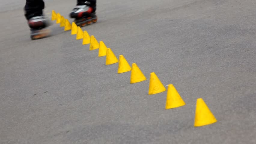 Experienced roller skater rides in park among yellow cones 