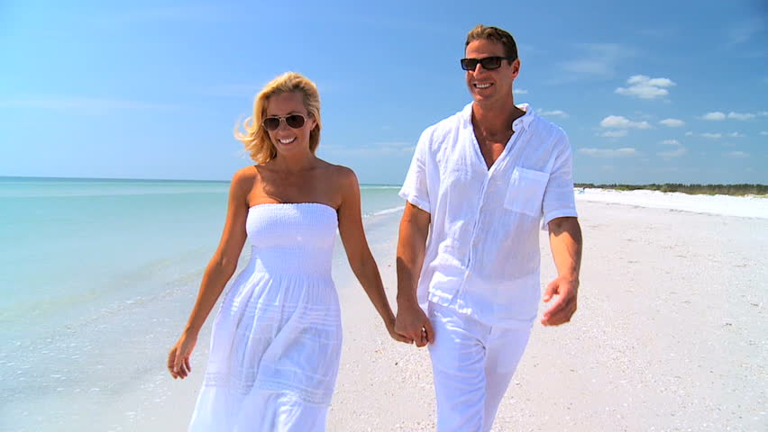 Attractive young caucasian couple in love walking together on the beach 60FPS