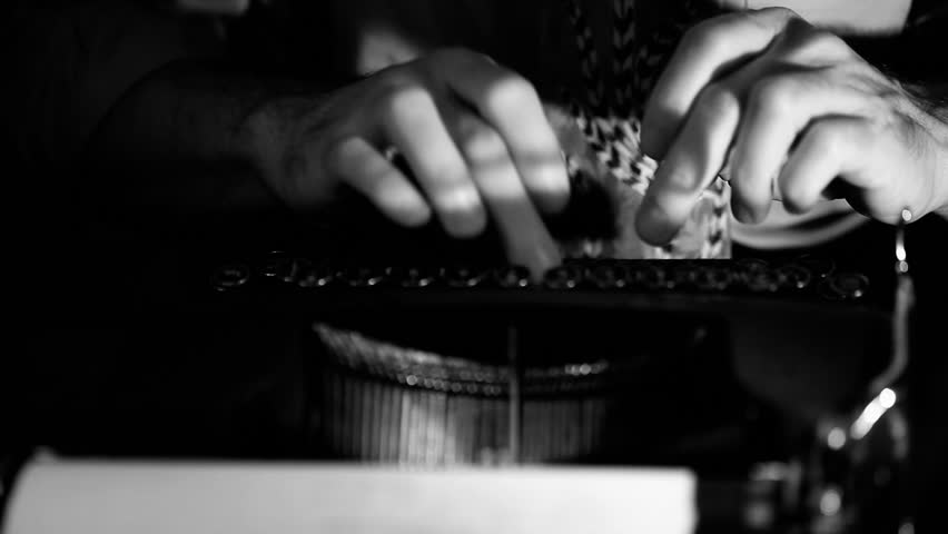 Light focuses on the hands of a man typing on a vintage 40's style manual typewriter. Film Noir Lighting and affect.