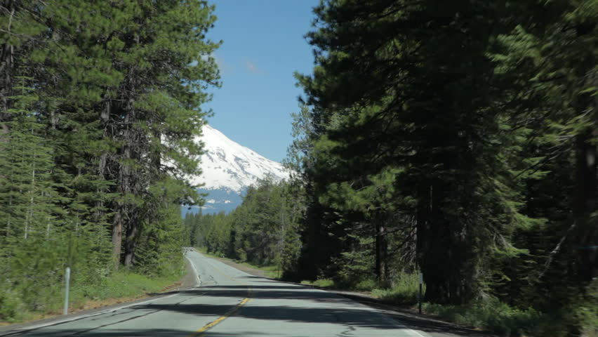 Driving on a 2-lane highway that curves to reveal a long, straight section that leads to a view of Mt Shasta in the background.