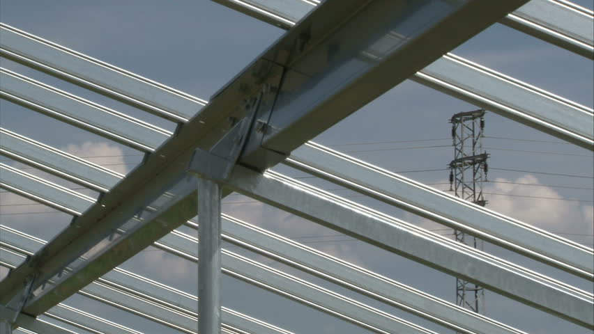 Worker is tightening up nut on metal solar power-plant construction.
