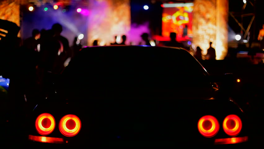 Car party. Beautiful sports car is in the center of night discos. The background is blurred.