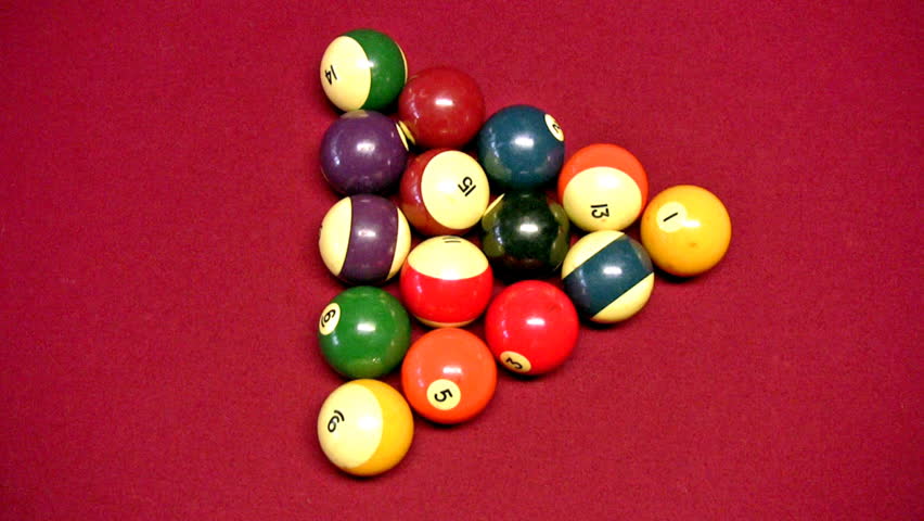 Video of a pool or billiards table with red felt covering. Pool balls being broke and scattering on table. Billiard recreation and family fun. 
