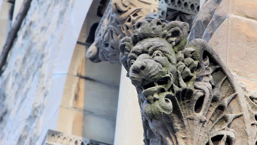 Static shot of a lion gargoyle on the side of a very old building.