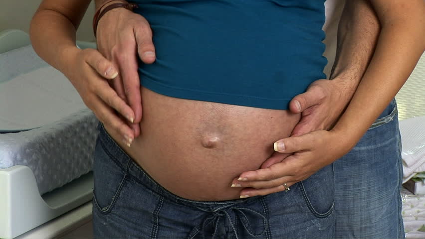 Close up of pregnant couple caressing belly 	