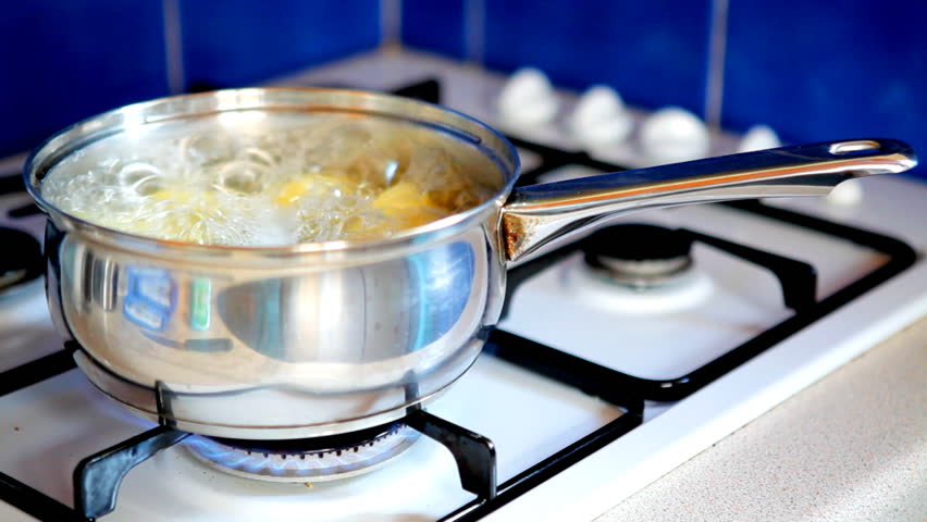 Potatoes boiling in a pan on a gas stove / oven