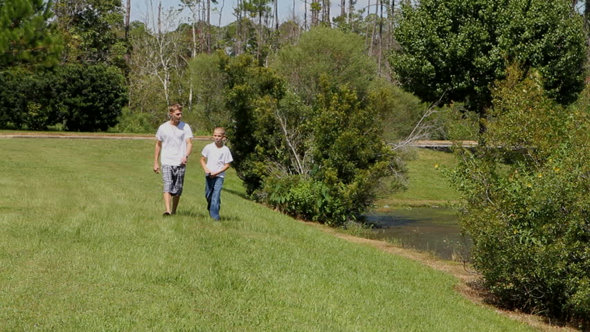 Two brothers, one seventeen, the other twelve, walk by a pond and talk to each other.