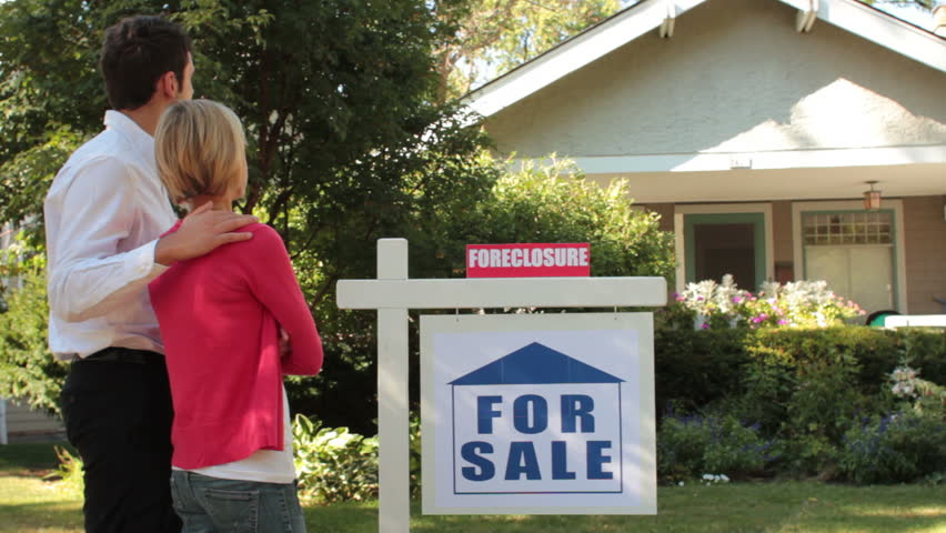 Couple standing in front of their foreclosed home