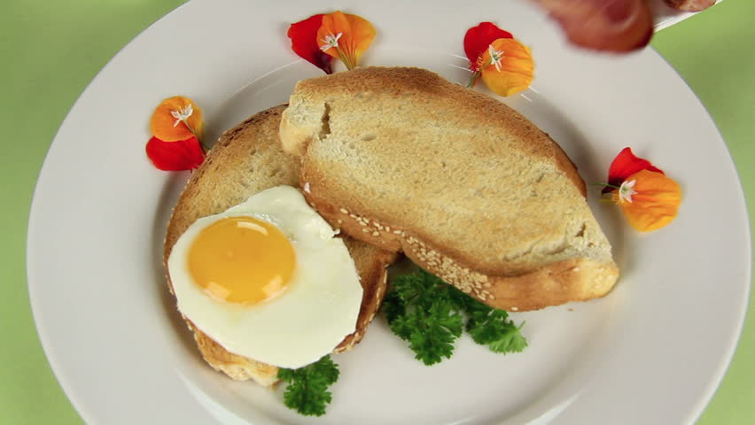 Edited sequence of preparing bacon and eggs for breakfast topped with baked beans. 