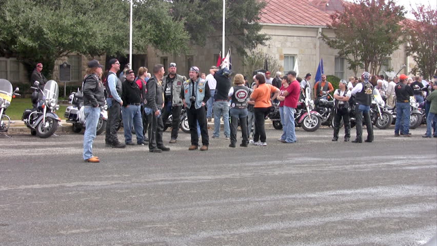 Video of a motorcycle rally on Veterans Day. Bikers and citizens group ready for ceremony. Handheld movement. 