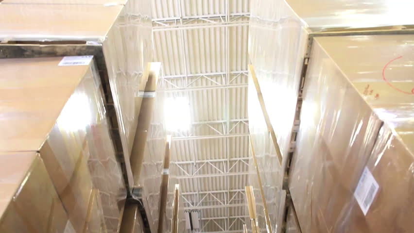 A warehouse foreman checks inventory amidst stacks of boxes 