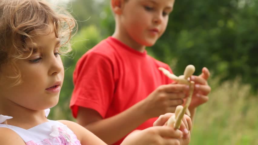 boy and girl are playing with dolls enthusiastically sunny summer day.