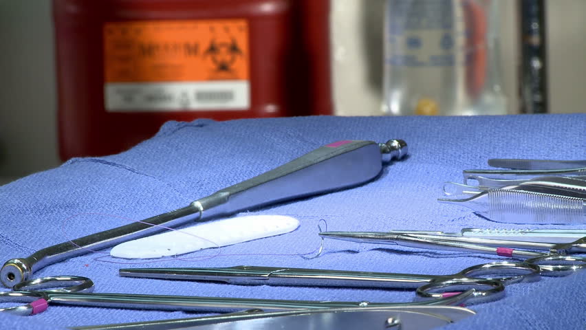 The hands of a surgical nurse picking up and exchanging instruments on a tray. 