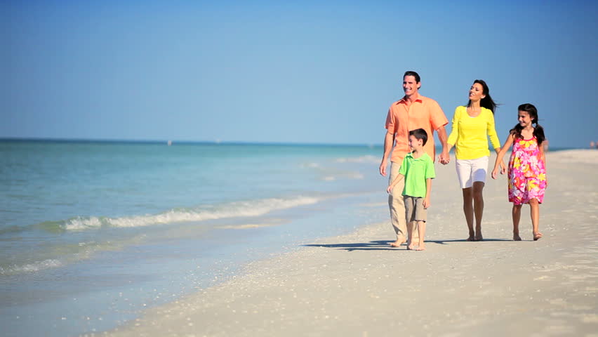 Attractive young family enjoying time together walking outdoors on the beach