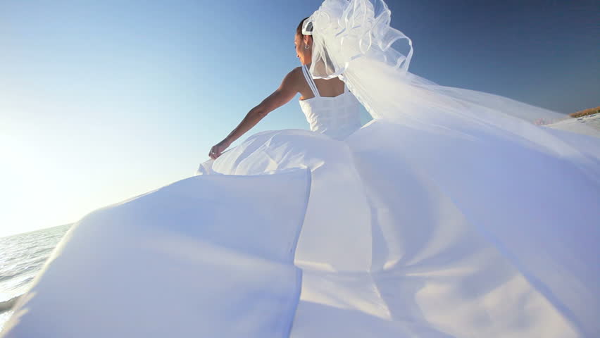 Beautiful bride in her wedding dress walking on the beach where she married