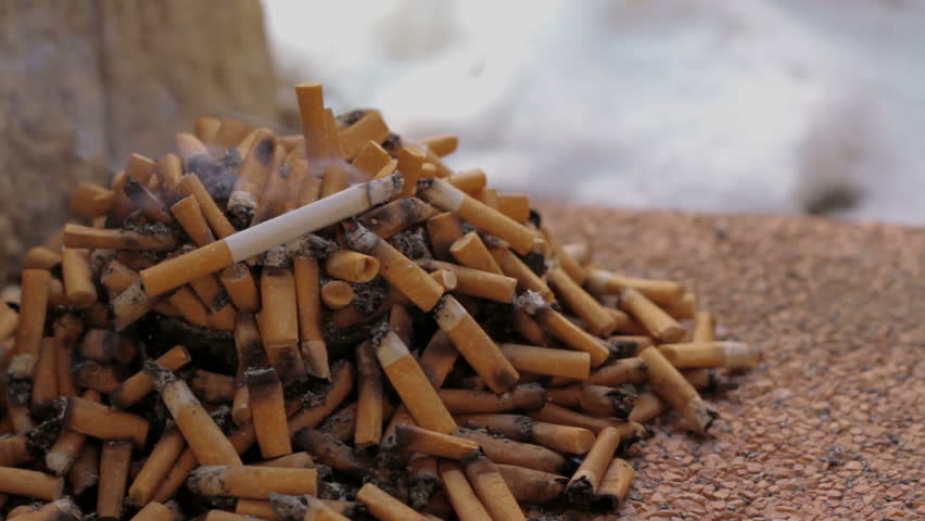 Full ashtray with Burning Cigarette