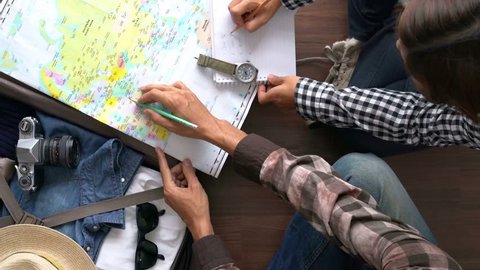 Overhead view of Traveler's Young couple planning honeymoon vacation trip with map. Top view.