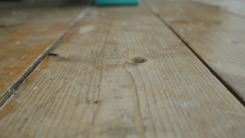 A Man Sanding Wax Off Wood Flooring With An Electric Sander