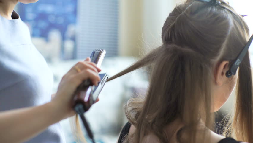Hairdresser Makes The Final Stage Of Creating A Hairstyle For A Cute