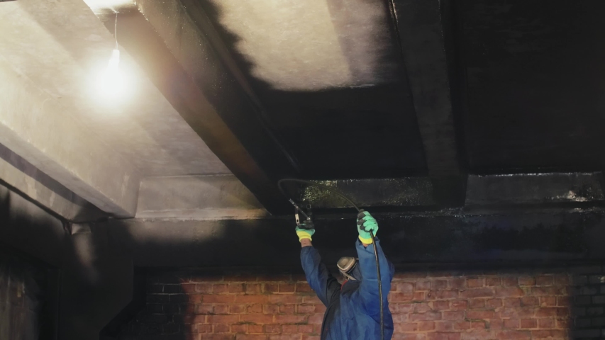 Worker Painting The Ceiling By Airless Spray Gun With Black Color