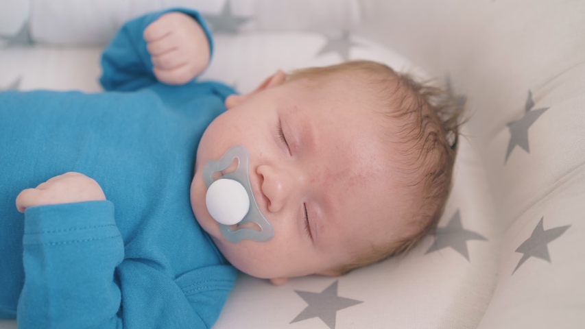 Lovely Newborn Baby With Pacifier Sleeps In Star Decorated Cocoon In