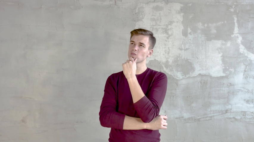 Young Man Burgundy Sweater Short Haircut Stands Against A Gray