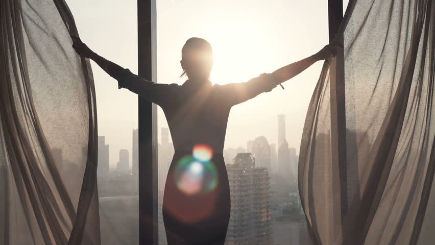 Young businesswoman unveil curtain and looking out of window
