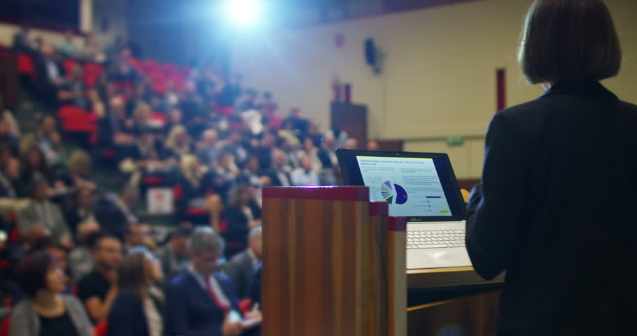 A woman holds a speech to the audience in an auditorium on a convention of economics and finance their business and to applaud his speech