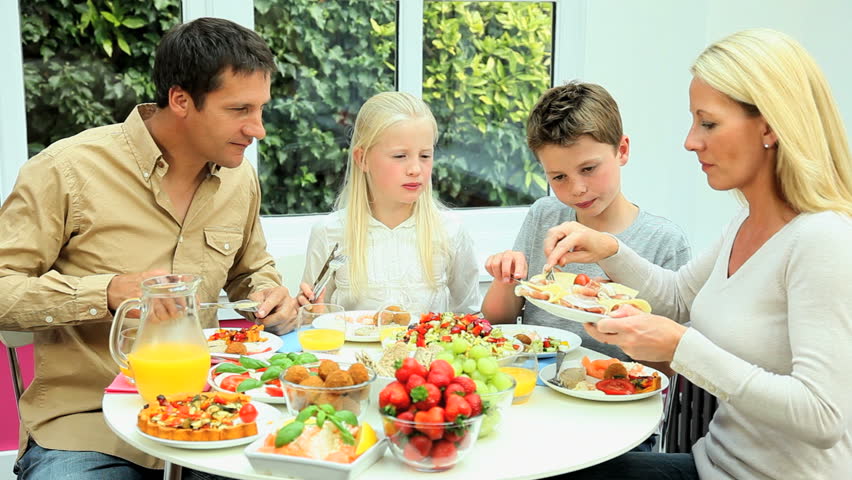 Young Family At Table Together Eating A Healthy Meal Stock Footage ...