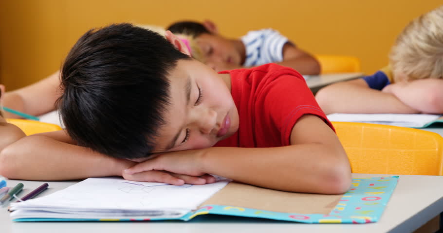 Side View Of Group Of Diverse School Kids Sleeping On Desk In