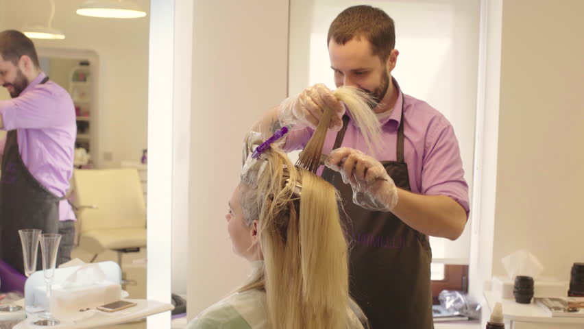 Brush Paint Over The Hair Roots From Blonde Close Up Hairdresser Dye The Hair Blonde Girl Sitting In A Beauty Salon Barber Brush