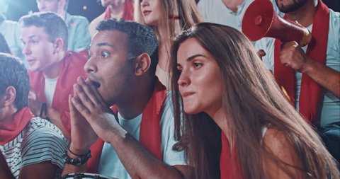 Group of fans watch a sport championship on stadium. People are dressed in casual cloth.