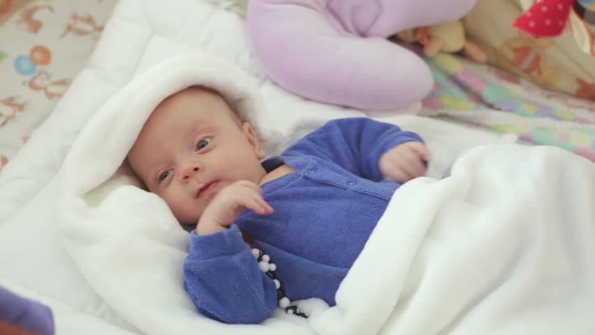 Newborn Baby Boy In Blue Clothes Is Awake In The Crib