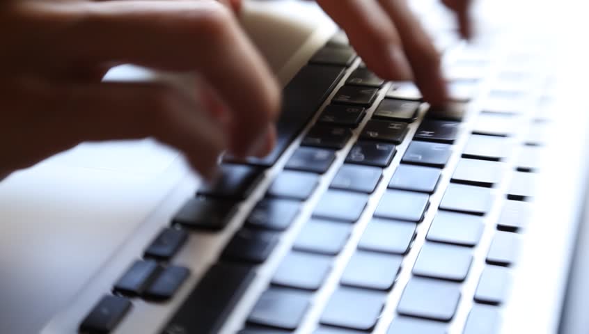 Close-up of a young woman typing on a laptop keyboard 