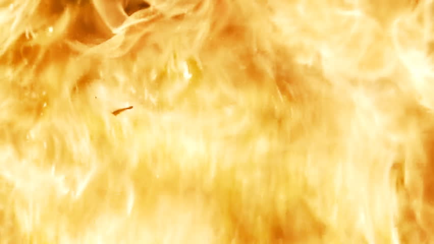 Bright, intense blast of flame, super close, with fragments burning in slow