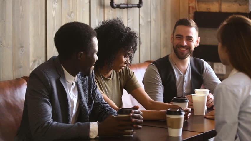 Multiracial Friends Drinking Coffee Together In Cozy Cafe 