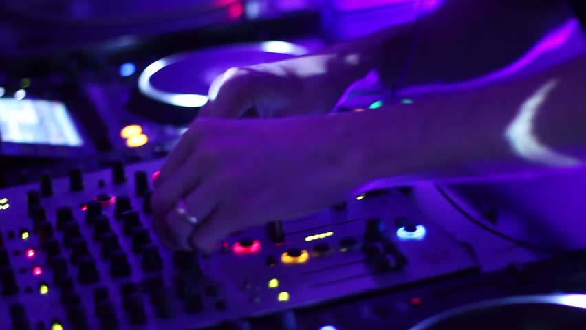 Hands of DJ tweak various track controls on dj's deck, camera is breathing