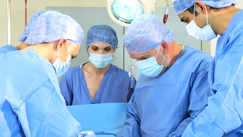 Senior Doctor Performing Operation Using Surgical Equipment Helped By ...