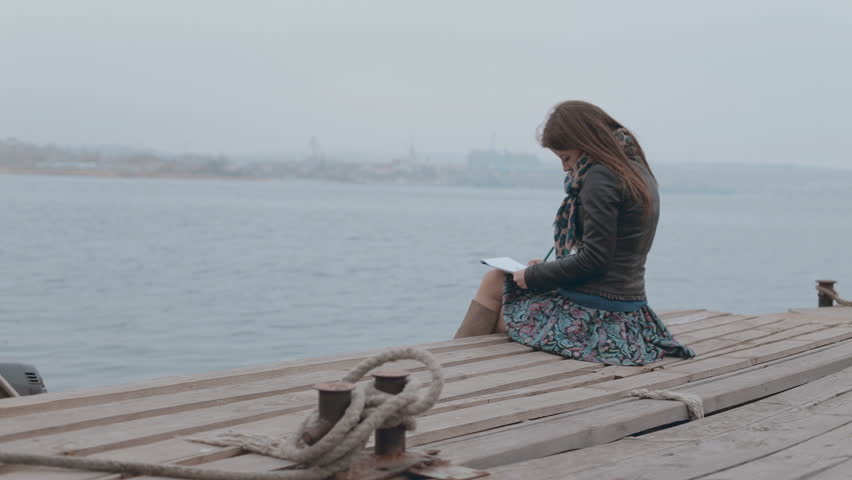 close up of a cute girl sitting on the dock and looking at